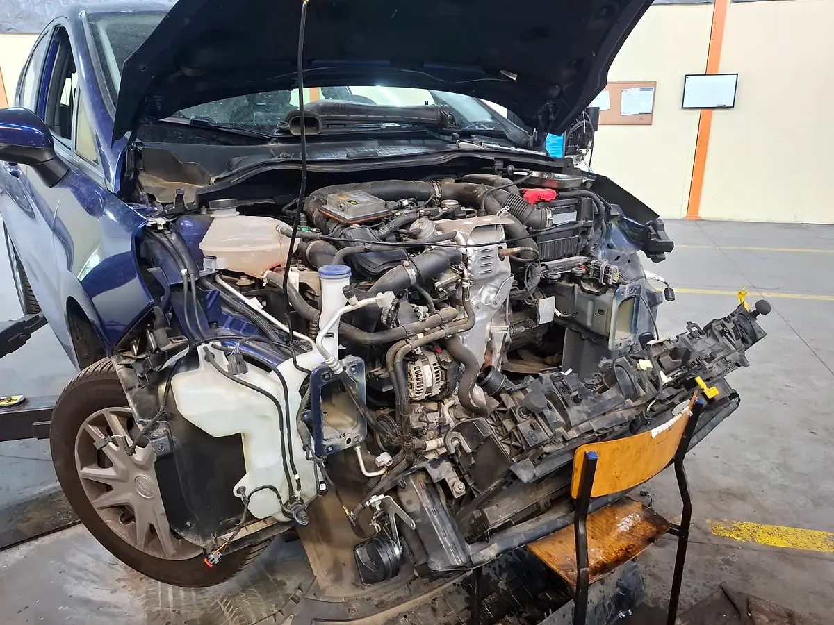 Auto po kolizji w warsztacie OlejNaMiejscu.pl: zdemontowany przód, widoczne uszkodzenia pasa i chłodnic